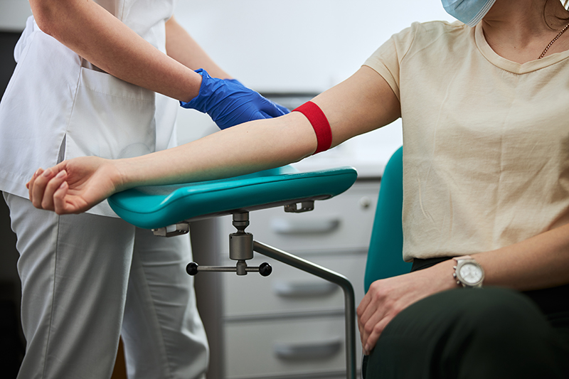 Image of a person sitting in a blood draw chair with a tourniquet on their arm
